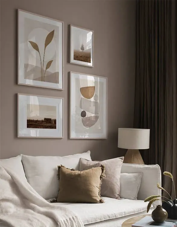 галерийна стена с различни размери рамки над светъл диван